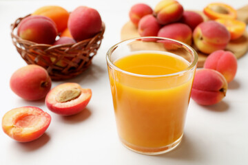 Apricot juice in glass and fresh fruits on white table, closeup © New Africa