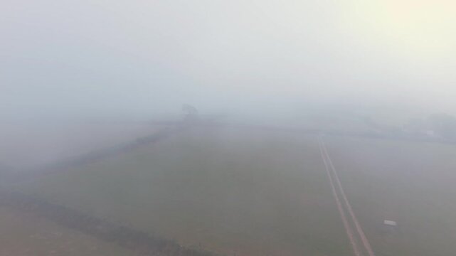 Slow flight aerial view over misty agricultural fields in Looe, Cornwall