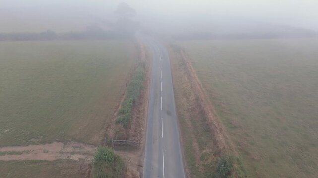 Aerial view of a winding country road through misty fields in Looe, Cornwall