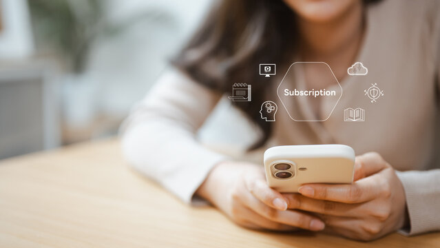 A woman checks a subscription interface on her smartphone to review recurring charges and examine billing details before deciding whether the account should continue past the next payment date.