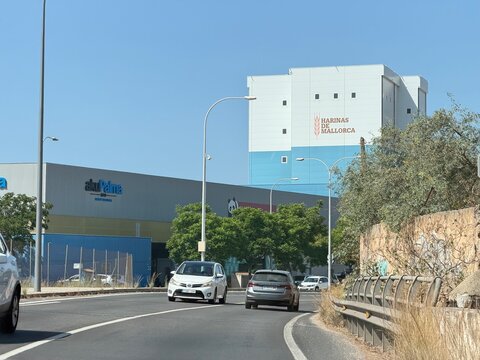 Palma, spain, august 2, 2026, harinas de mallorca flour mill building on an industrial road with cars and aku palma store under a clear blue sky