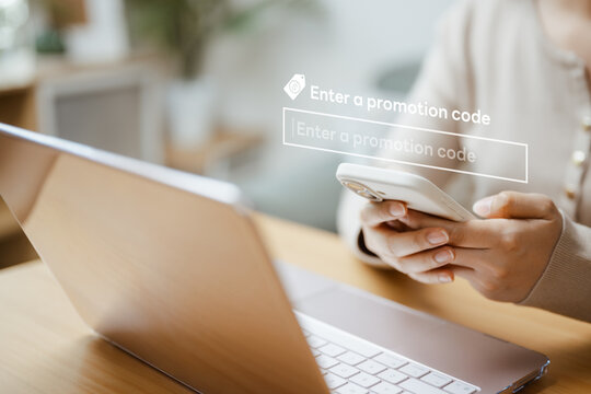 A shopper enters a code on a smartphone beside a laptop as a promo applies a discount to the online basket before the customer completes payment for selected products during a seasonal campaign.