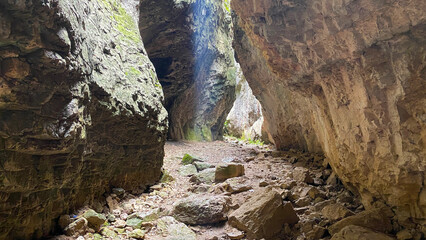 Erosion shapes rock canyon, interior wide view through fractured stone walls and fallen blocks in...