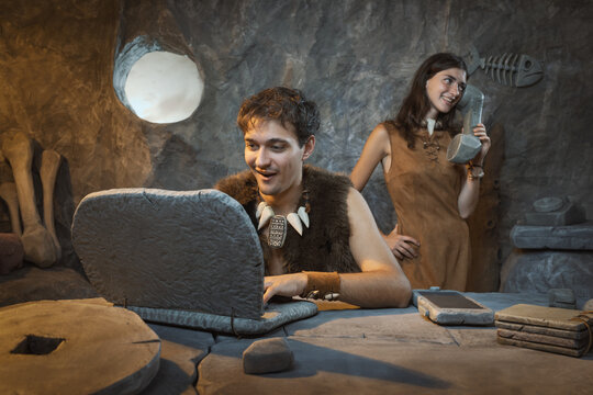 Prehistoric couple using devices in their cave