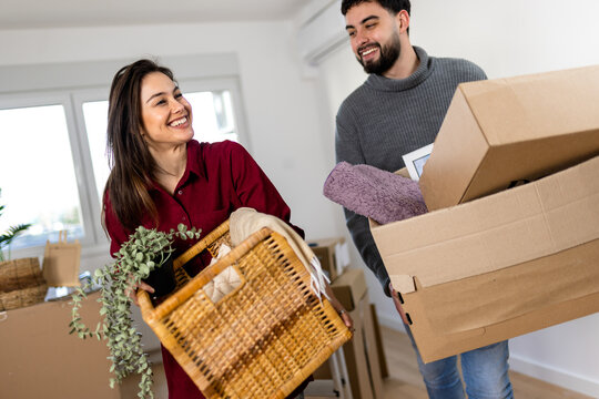 Couple carrying cardboard boxes and a wicker basket during a home move