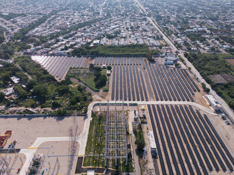 Aerial view of the CFE solar farm and electrical substation, featuring rows of solar panels, power transmission towers, and surrounding urban infrastructure in Merida, Yucatan, Mexico.