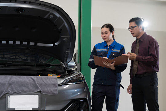 Mechanic inspects and repairs car engine and components with hood open inside services garage