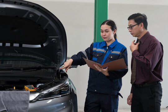 Mechanic inspects and repairs car engine and components with hood open inside services garage