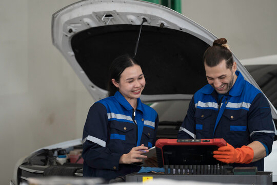 Group of mechanic inspects and repairs car engine and components with hood open inside services garage