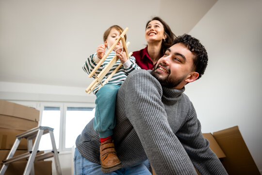 Father carrying his young son on his back while the family moves home