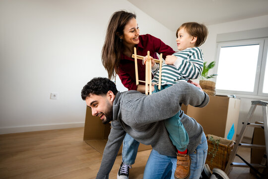 Father carrying his young son while mother stands beside them at home