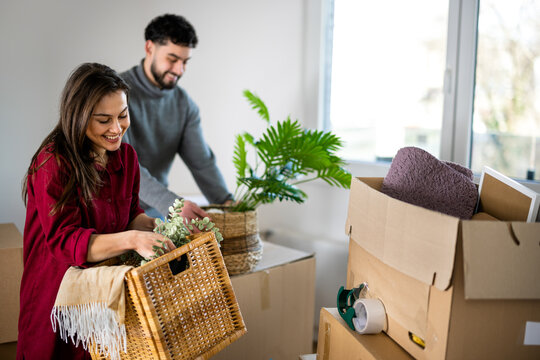 Woman carrying a wicker basket among moving boxes at home