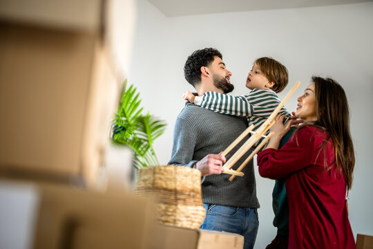 Family lifting a young boy among cardboard boxes during a home move