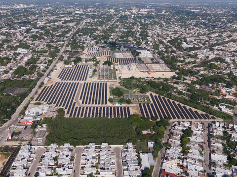 Aerial view of the CFE Merida Area solar farm and electrical substation featuring rows of solar panels and industrial infrastructure surrounded by residential neighborhoods in Merida, Yucatan, Mexico.