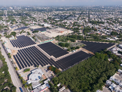 Aerial view of the CFE Merida Area solar farm featuring rows of photovoltaic panels, electrical infrastructure, and surrounding urban landscape in Merida, Yucatan, Mexico.