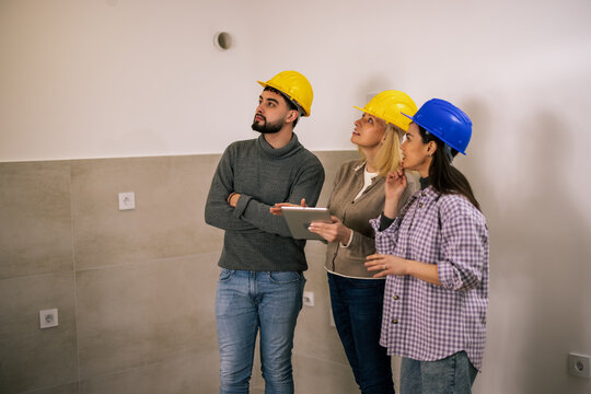 Construction team reviewing renovation plans on a tablet in an unfinished room