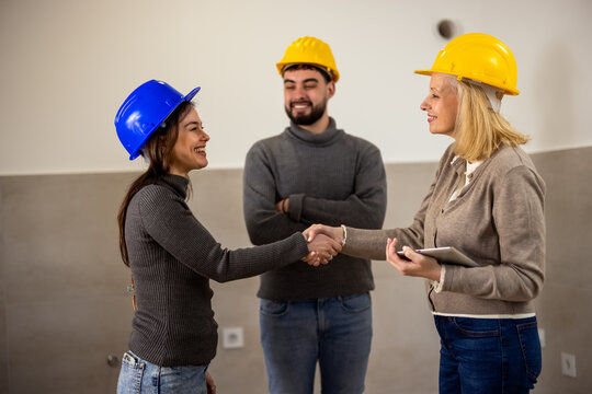 Construction professionals shaking hands during a building renovation project