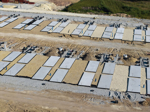 Aerial view of construction site with rows of concrete foundations and gravel paths in Poland.