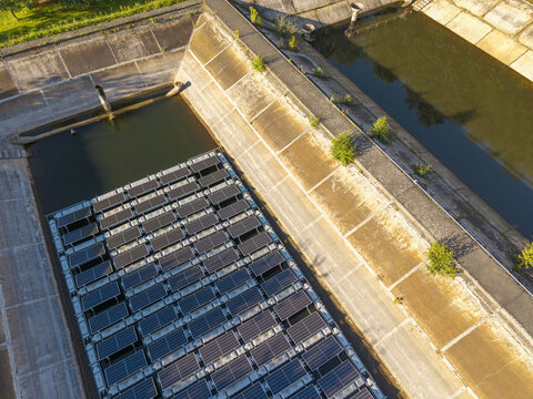 Aerial view of a floating solar farm with photovoltaic panels installed on a water reservoir surrounded by concrete embankments in Poland.