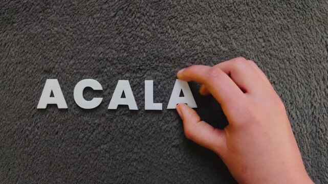 persona escribiendo la palabra acalasia en un fondo oscuro con letras blancas y pre hechas (versi&oacute;n r&aacute;pida)