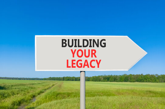 Building your legacy words symbol. Concept words Building your legacy on beautiful grey road sign. Beautiful blue sky green grass background. Business building your legacy concept. Copy space.