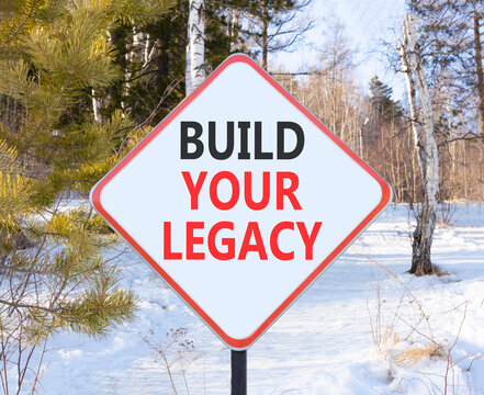 Build your legacy words symbol. Concept words Build your legacy on beautiful white road sign. Beautiful winter forest background. Business build your legacy concept. Copy space.