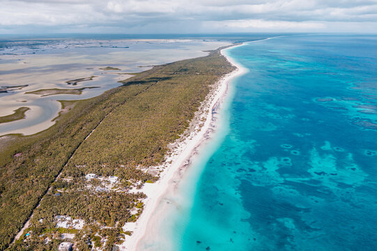 Aerial view of the coastline in Tulum featuring turquoise Caribbean waters, white sandy beaches, and dense tropical jungle vegetation in Tulum, Quintana Roo, Mexico.