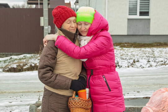 Caring daughter hugging senior mother outdoors in winter after being found. Emotional reunion of elderly woman with dementia and family after missing search, social support and relief concept