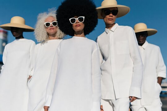Minimalist group of diverse models in white outfits with wide brim hats for fashion campaign banner and editorial background