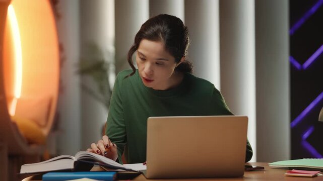 Korean female student works on university project in library, typing on laptop