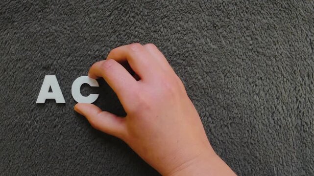 persona escribiendo la palabra acalasia en un fondo oscuro con letras blancas y pre hechas (versi&oacute;n lenta)
