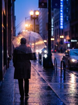 Person Walking with Umbrella in Rainy City