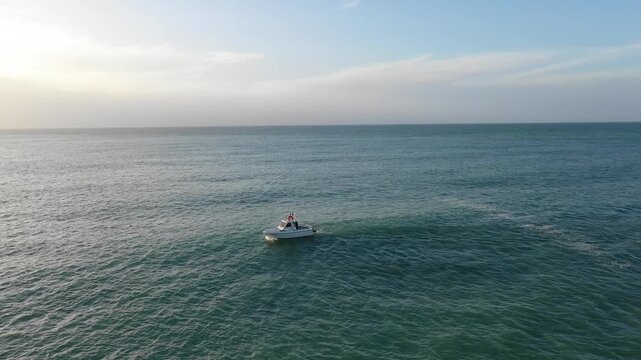 A small motorboat floats on the calm sea near Fecamp in Normandy, France, during sunset. Filmed in the Alabaster Coast, Normandy, France.