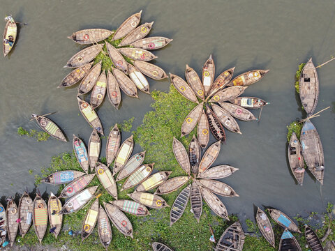 Aerial view of wooden boats arranged in a flower-like pattern on the Buriganga River in Dhaka, Bangladesh.