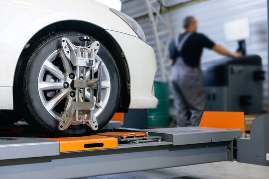 Vehicle inside garage workshop for auto camber fixing work. Closeup car wheel alignment on stand with sensors check in service station