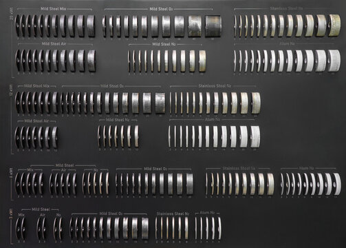 Industrial metal cutting test samples arranged by material, thickness and laser cutting parameters, including mild steel, stainless steel and aluminum