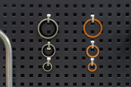Rubber O-rings and bonded copper washer seals hanging on perforated metal pegboard wall in workshop.