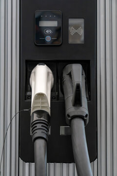 EV charging station panel with dual cables, contactless pay reader, and green LED accent lights for eco-friendly vehicle refueling