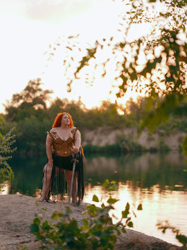 Plus Size Redhead Warrior Woman Standing With Sword Outdoor by Lake