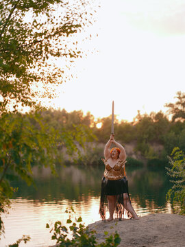Plus Size Redhead Warrior Woman Raising Sword Outdoor by lake