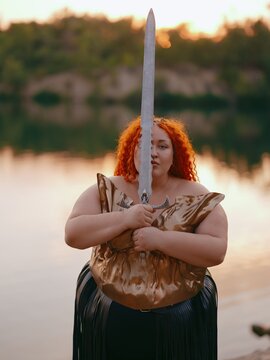 Plus Size Warrior Woman Holding Fantasy Sword by Face