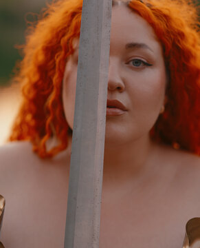 Plus Size Warrior Woman Holding Fantasy Sword by Face
