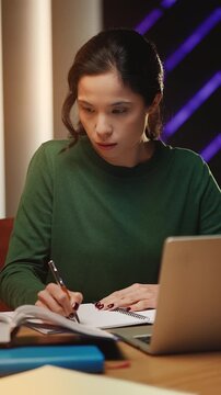 Korean female student does research, writing notes and reading a library book