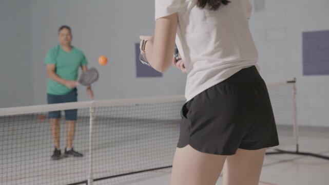 Pickleball players in a modern school gym co-ed practicing and having fun