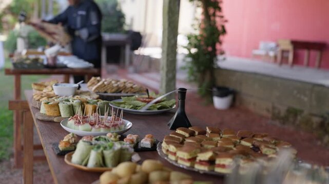 Buffet table with mini sandwiches wraps canapes and skewers set outdoors for an event