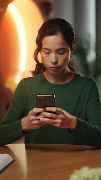 Young Korean woman scrolls social media on phone while working online from home