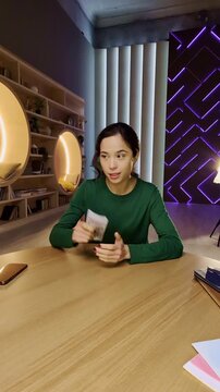 POV of young Korean woman recording video for financial blog in home study