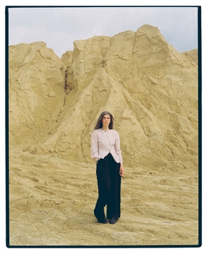 Woman stands against vast arid hills under an overcast sky