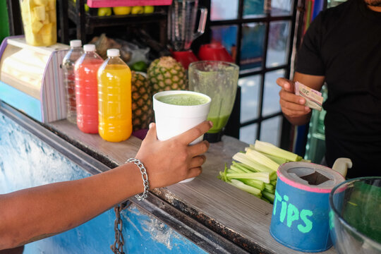 Hand Reaches for Fresh Juice at Street Stand