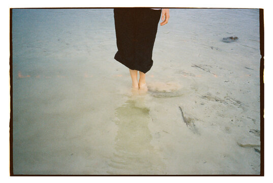 Bare feet wading in tranquil nature water on film